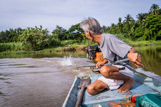 A fisherman turns his longtail boat on a river in Thailand