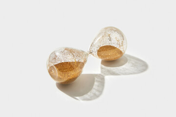 Hourglass with golden sand inside lying on white background
