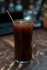 Drink on a dark background of a bar. Alcoholic drink with wooden shaker on a bar counter. Close up of a nightclub drink.