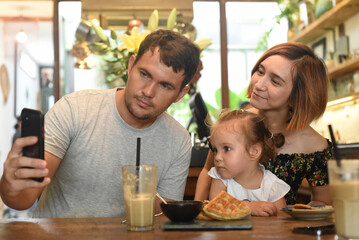 Young family making selfie in a caf&eacute;