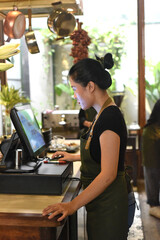 Young Vietnamese waitress serving a customer at the checkout in cafe