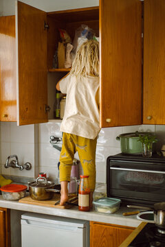 Little boy peeking into the cupboard in the kitchen