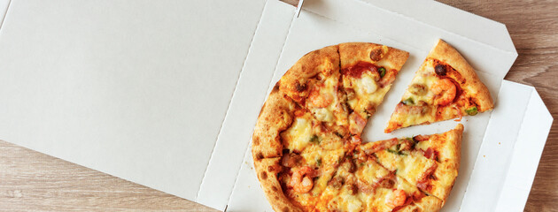 Pizza in a delivery cardboard box on the table. テーブルの上のデリバリー用の箱に入ったピザ
