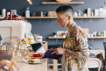 Woman using phone at cafeteria bar