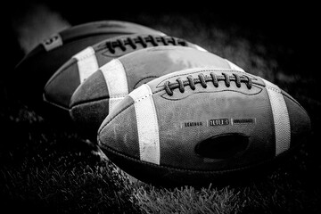 A row of old footballs on a football field, black and white