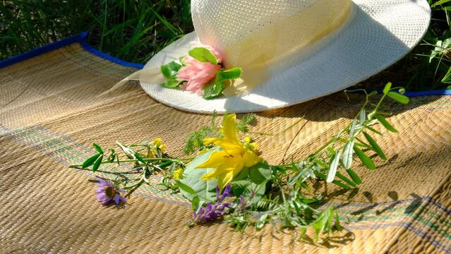 Summer scene, straw hat, meadow flowers on bamboo mat ,rug. Relaxing in the shade, enjoying nature