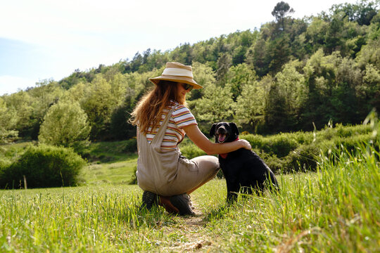 happy Young woman playing with dog in sunny field in nature