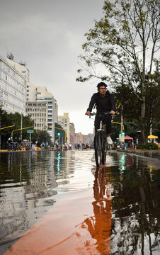 Joven montando bicicleta en una calle inundada de la ciudad de Bogot&aacute;, Colombia