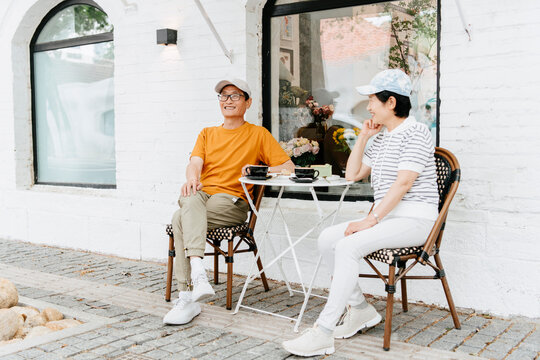 mature couple with hat enjoying coffee and dessert outdoors on street