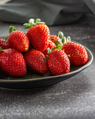 red fresh and delicious strawberries on a dark plate. dark food photography
