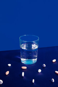 Pills around a glass of water