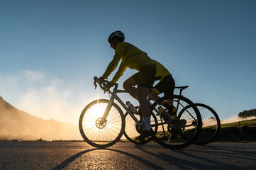 Sportsman and sportswoman riding bike on misty morning