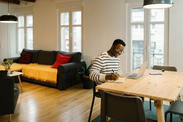 Smiling young man studying with computer at home