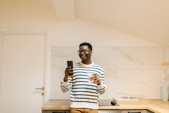 Smiling male looking at cellphone in the kitchen