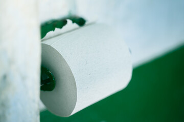 Toilet paper holder with cheap low quality single ply toilet paper close up. Untidy scary rural toilet room