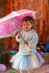 Beautiful little girl having fun smiling and playing with a pink umbrella. 