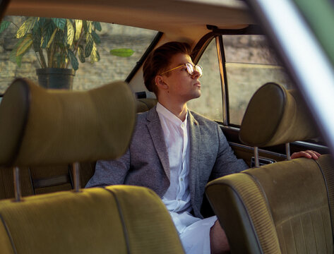 A stylish man inside a car with  sunlights