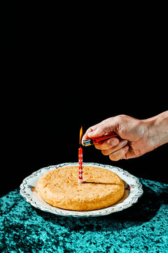 man lighting a birthday candle on a spanish omelette
