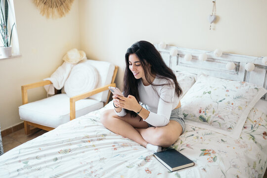 Young woman using smartphone in bed