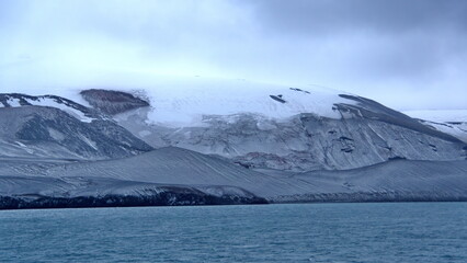 Snow dusted mountains surrounding a crater bay on Deception Island, Antarctica