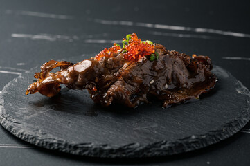 A dish of sliced and roasted Japanese beef on top of rolled vinegared rice,Wagyu sushi on black plate.