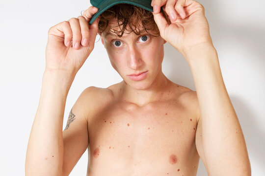 Young shirtless man with green cap on his head