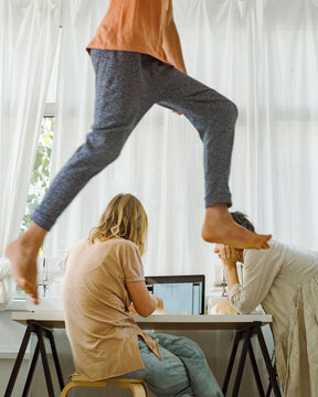 A young boy jumps against the background of his mother in room