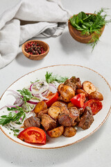 Traditional georgian dish odjahuri with meat and potatoes. Roasted pork fillet and potatoes with onion and tomatoes. Stew meat and potatoes. Eastern food with pork and spices