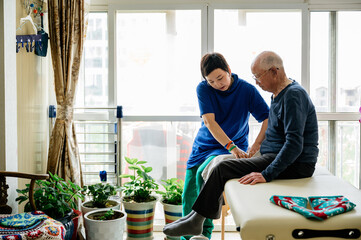 Physical therapist helping senior man patient to massage his legs