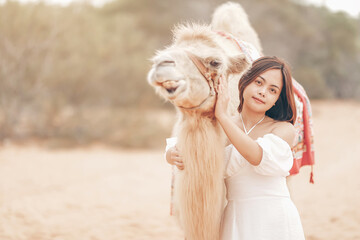 Portrait of  asian young woman  tourist in white dress and landscape with tourists riding on camels is popular travel destination in Mui Ne desert, Vietnam