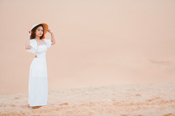 Fototapeta na wymiar Portraits of woman with white dress walking on a bright summer day, in the Mui Ne desert Vietnam holliday vacation concept.