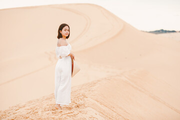  Portraits of  woman with white dress walking on a bright summer day, in the Mui Ne desert Vietnam...