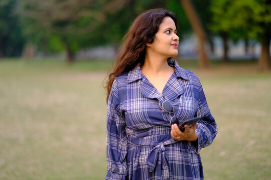 Pretty and active Indian woman standing in a greenfield in daytime