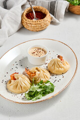 Steamed dumplings shrimp in asian style on white concrete background. Prawn dim sum with sauce on ceramic plate. Shrimp wontons on dish in minimal style. Asian dumplings with seafood.