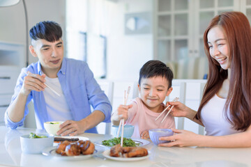 Obraz na płótnie Canvas little boy enjoy eating food with father and mother. Happy Asian family having dinner at home
