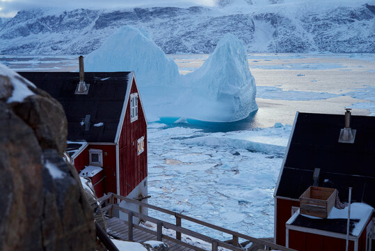 Massive iceberg and outlying settlement houses, Greenland