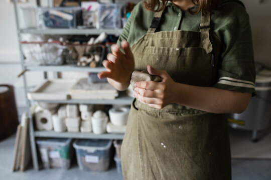 A ceramist woman holds a piece of clay in her hands