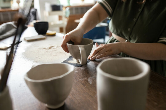 Young craftwoman using sandpaper to scrub the mug