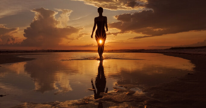 Silhouette of Woman Walking a Sunset Beach 