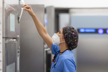 nurse with facemask, working with  Washer Disinfector Machine.
