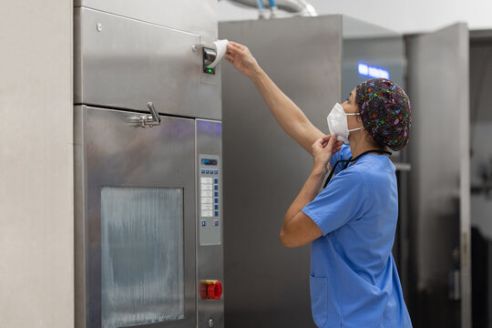 nurse with facemask, working with  Washer Disinfector Machine.