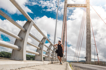 man contemplating the view from a large bridge with tension cables in the green gulf of Costa Rica in Guanacaste