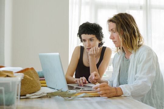Two young women discussing dress design