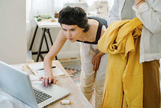 Two women discussing dress design in atelier studio 
