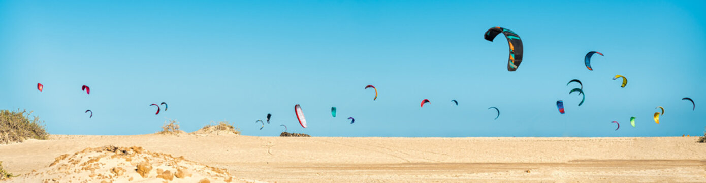 Many kitesurfers on the beach skyline are getting ready to practice Kitesurfing on the Corralejo dunes beach in Fuerteventura, Canary Islands. Spain - Extreme sports concept