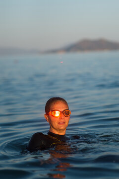 Young woman in a wetsuit with a sun reflection in her goggles