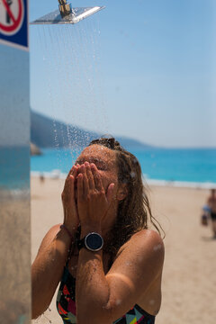 attractive Young Female enjoys cold shower On The Beach
