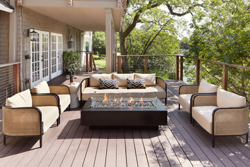 Outdoor furniture sitting area and fireplace on backyard deck of home