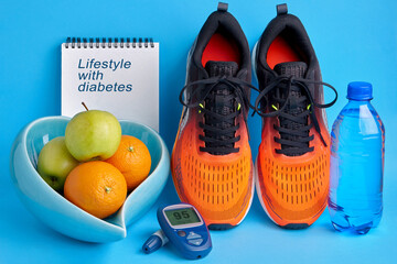 Orange sneakers, a notebook diary, a glucometer, a bottle of drinking water and fruits on a blue...
