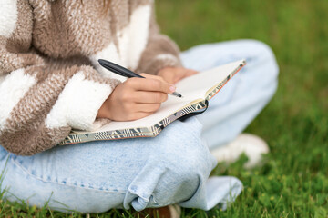 Girl writing notes with pen while sitting in the street.